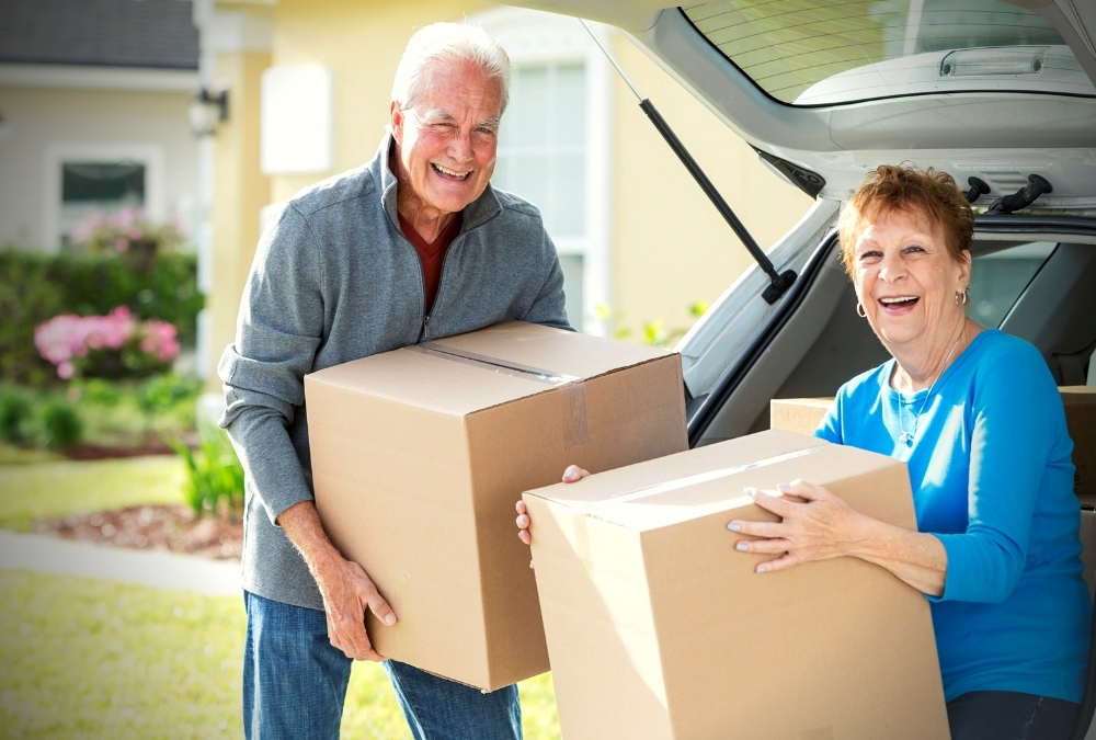 Senior man and woman unloading boxes from a car