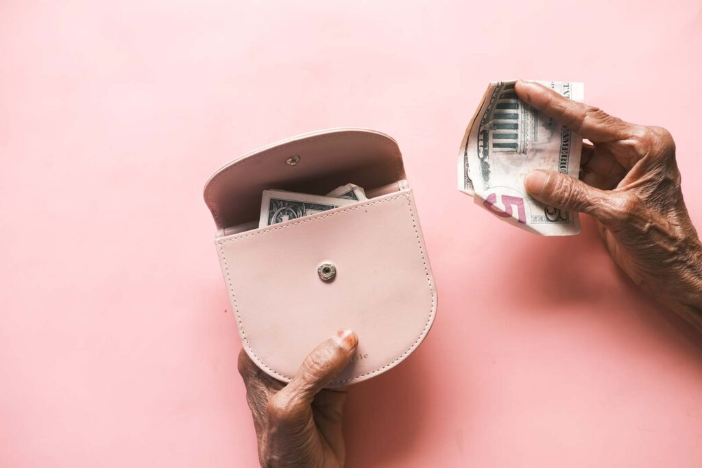 Close up of a senior holding a pink coin purse with money visible inside