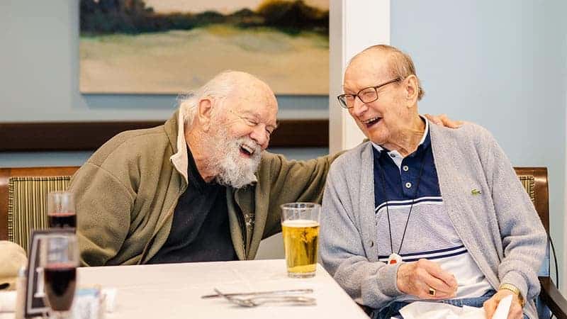 Senior men seated in the lounge laughing over a beer